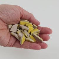 Video of Flip ceramic puzzle pieces in corn, opaque glazed porcelain, 4–20 mm, held in a hand and poured out to show their shapes and finish