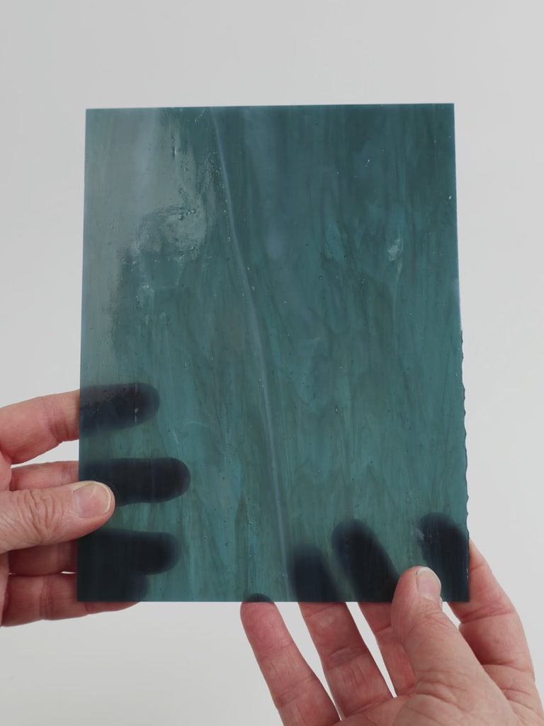 Video of the petrol grey glass plate in grey translucent marbled, 15x19cm, held up and tilted to show its pattern and transparency