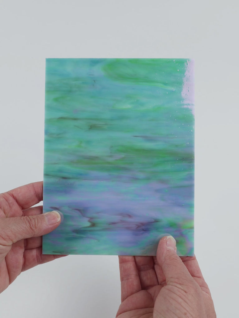 Video of the Soft teal Marbled Iridised glass plate in iridised translucent teal, 15x19cm, held up and tilted to show its pattern and transparency